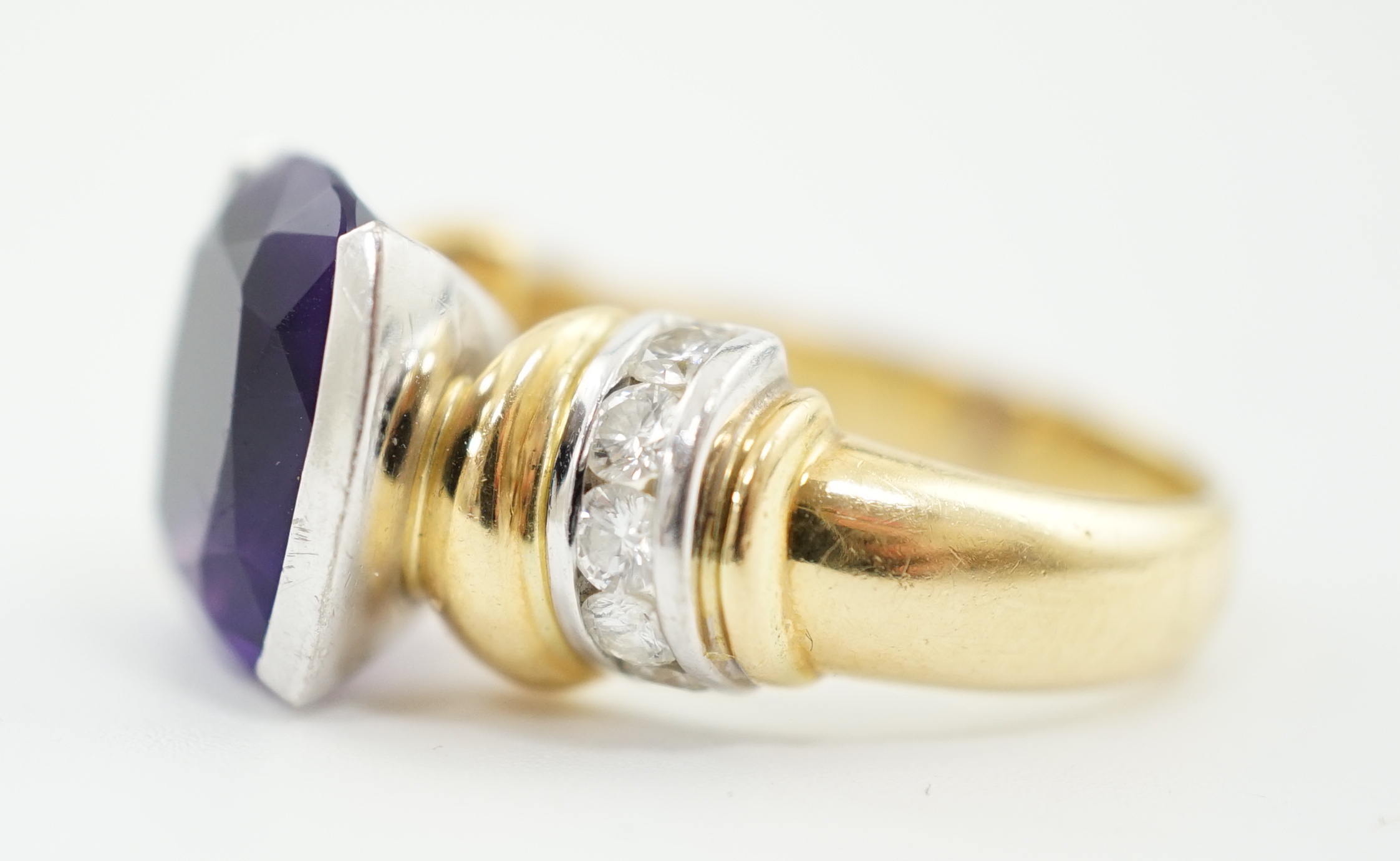 A modern 18ct gold and single stone cushion cut amethyst set dress ring, with ten stone round brilliant cut diamond set shoulders